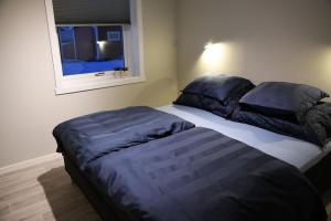 a bedroom with two beds with blue pillows and a window at Leilighet med strandbeliggenhet in Ramberg
