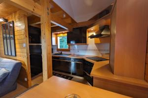 - une cuisine dans une cabane en rondins avec cuisinière dans l'établissement Chalet nordique au coeur de la Feclaz, à La Féclaz