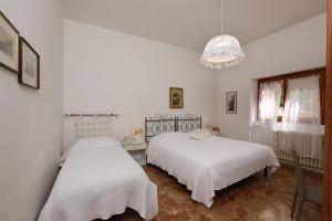 two beds in a white bedroom with a chandelier at villa oliveta in San Gimignano +64 photos