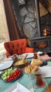 a table with plates of food and a fireplace at AYDER BUNGALOW - river view , Royal Bungalow Resorts in Çamlıhemşin