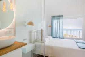 un bagno bianco con lavandino, letto e finestra di Cap Sa Sal Aquamarina Begur a Begur