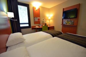 a hotel room with two beds and a television at Kyriad Dijon Est Mirande in Dijon