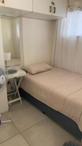 a small bedroom with a bed and a desk at Toti Cabana 58 in Amanzimtoti