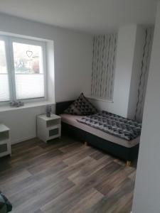 a small bedroom with a bed and two windows at Ferienwohnung I Sarrebriese in Bottmersdorf