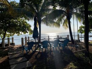 una mesa y sillas sentadas bajo palmeras en la playa en Ocean fronthouse in Salinitas en Acajutla