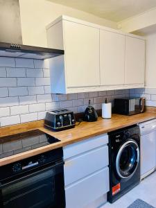 a kitchen with a counter with a microwave and a washer at The Cwtch - Apartment in Cardiff/Penylan in Cardiff