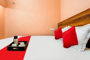 Schlafzimmer mit einem Bett mit roten und weißen Kissen in der Unterkunft OYO Hotel Swagat in Zirakpur