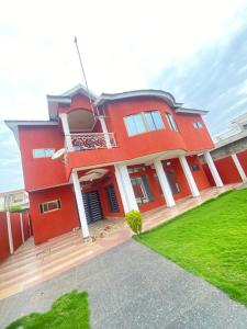 a red house with a balcony and a lawn at Villadeluxe3 in Abomey-Calavi