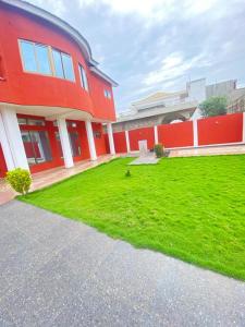 a red building with a green lawn in front of it at Villadeluxe3 in Abomey-Calavi
