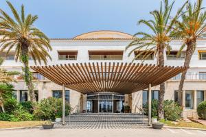 a large building with palm trees in front of it at Cap Sa Sal Aquamarina Begur in Begur