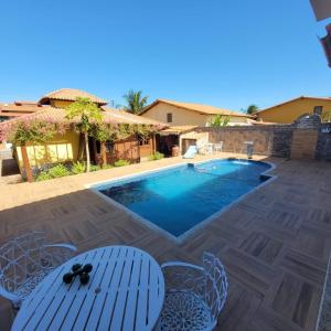 a pool with chairs and a table and a house at Cakau House - espaço amplo e aconchegante in Maricá