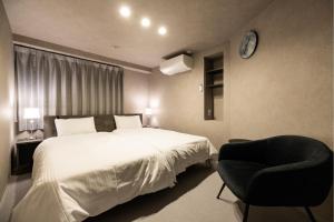 een slaapkamer met een bed en een stoel en een klok bij Lumiebelle - Vacation STAY 35183v in Kochi