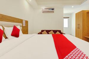 1 dormitorio con 1 cama blanca grande con almohadas rojas en Super OYO Flagship Aura Hotel Rajdhani Residency, en Ranchi