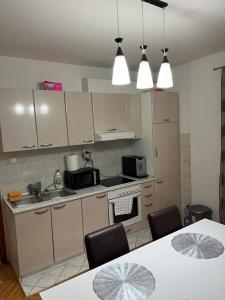 a kitchen with white cabinets and a table with chairs at Stan na dan Apartman TRG in Derventa
