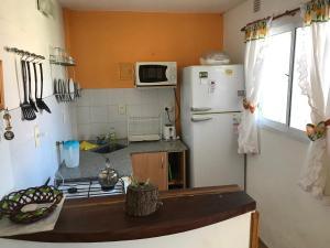 Elle comprend une petite cuisine équipée d'un réfrigérateur blanc et d'un évier. dans l'établissement Complejo El Pinar, à Las Grutas