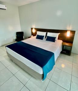 a bedroom with a large bed with blue and white sheets at Hotel Adventure São Luís in São Luís