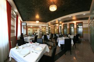 a dining room with white tables and black chairs at Hotel Seneca in Baia Mare