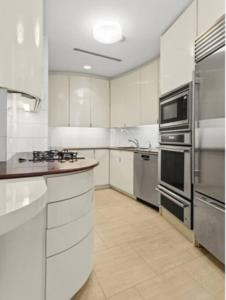 a large kitchen with white cabinets and stainless steel appliances at Private Beautiful Townhome w Zen Garden in New York