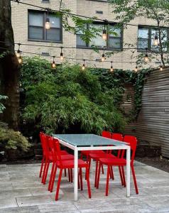 Private Beautiful Townhome w Zen Garden في نيويورك: طاولة مع أربعة كراسي حمراء جالسة حوله