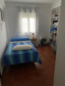 een slaapkamer met een blauw bed en een raam bij Habitación luminosa en piso compartido in Mairena del Aljarafe