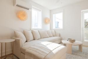 a white living room with a couch and two windows at The Atlantic at The Tarrymore in Wrightsville Beach