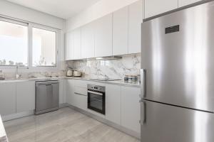 eine Küche mit weißen Schränken und einem Kühlschrank aus Edelstahl in der Unterkunft YAMAS Urban Living Sunny Pool Penthouse in Limassol