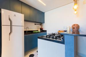 a kitchen with blue cabinets and a white refrigerator at Seaside #16 - Flat em Ponta Negra por Carpediem in Natal