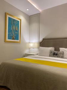 a bedroom with a large bed with a painting on the wall at Rosewood Lahore in Lahore