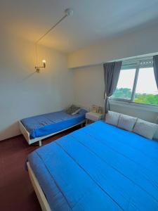 1 dormitorio con 2 camas con sábanas azules y ventana en departamento playa grande en Mar del Plata