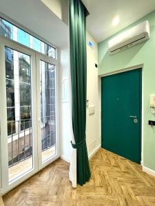 - une porte verte dans une chambre dotée de grandes fenêtres dans l'établissement Loft in Borgo, à Naples