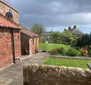 un jardín con un edificio de ladrillo y un patio en St Annes Crail- grand family home en Crail