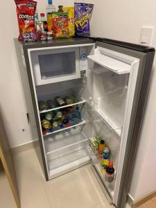 um frigorífico aberto cheio de bebidas e snacks em Apartamento en Barranco em Lima