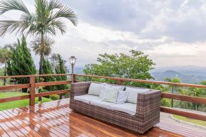 - un canapé en osier sur une terrasse en bois avec vue dans l'établissement Vivenda Mirante Do Sol, à Contagem