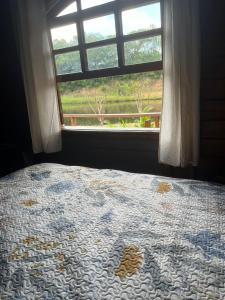 um quarto com uma cama e uma janela com um cobertor em Chalé aconchegante em Itu