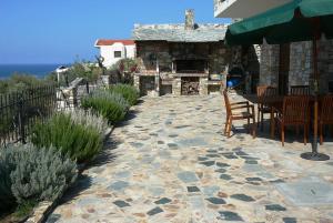 patio con mesa, sillas y chimenea de piedra en St.Nikola house, en Astris