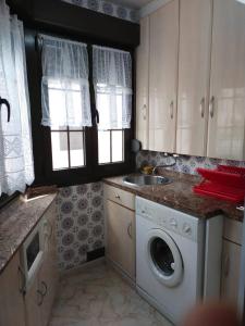 een keuken met een wasmachine en een wastafel bij El refugio de lastres in Lastres