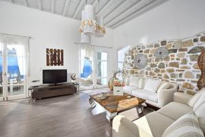 a living room with a white couch and a stone wall at Mykonos Sea View Luxury villa by Calypso sunset Villas in Mýkonos City