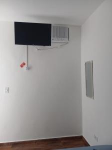 telewizor z płaskim ekranem wiszący na białej ścianie w obiekcie Pousada Believe w mieście Praia Grande