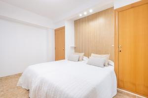um quarto com uma grande cama branca com lençóis brancos em Apartamento Currus Miramar Playa em Benidorm