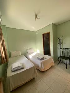 um quarto com duas camas e uma cadeira em Hotel Mendes Azevedo - próximo ao Araguaia Shooping, Rodoviária e a REGIÃO 44 - By Up Hotel em Goiânia