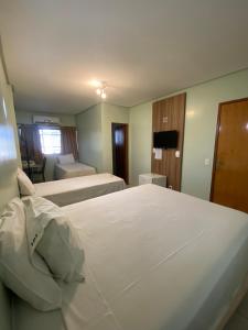 um quarto de hotel com duas camas e uma televisão em Hotel Mendes Azevedo - próximo ao Araguaia Shooping, Rodoviária e a REGIÃO 44 - By Up Hotel em Goiânia
