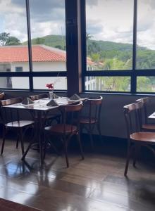 a dining room with a table and chairs and windows at Quinta de Santa Bárbara in Pirenópolis