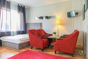 um quarto com duas cadeiras vermelhas e uma cama em Hotel Jastrzębia Góra em Jastrzebia Gora