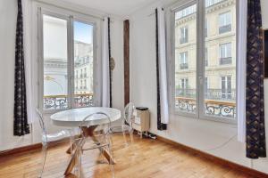 Zimmer mit einem Tisch und 2 großen Fenstern in der Unterkunft Charming T2 in 2nd arrond of Paris - Welkeys in Paris