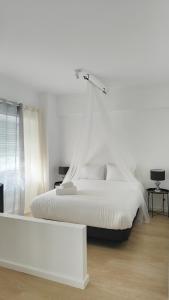 a white bedroom with a white bed and a window at Villa Paraíso da Caparica in Charneca