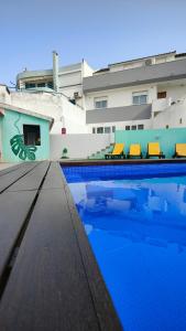 a swimming pool with blue water in front of a building at Villa Paraíso da Caparica in Charneca