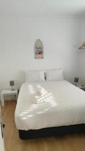 a white bed in a room with two tables at Villa Paraíso da Caparica in Charneca