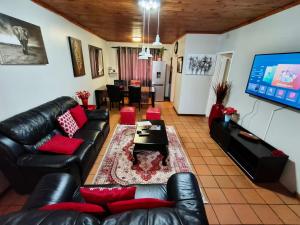 a living room with black leather furniture and a flat screen tv at Sabie House -3 bedrooms, OR Tambo, Kempton Park, Johannesburg in Kempton Park