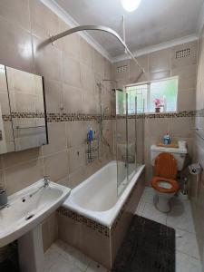 a bathroom with a tub and a toilet and a sink at Sabie House -3 bedroom house in Kempton Park