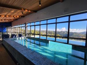 a large swimming pool with a large wall of windows at Wanderlust Experience Hotel Best Western in Campos do Jordão